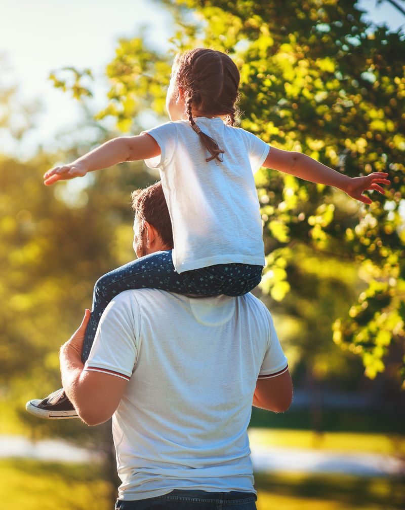 A child sitting on their dad shoulders 